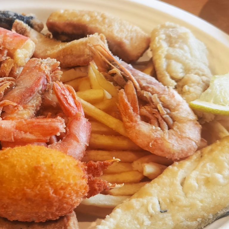 Le fritture di pesce fresco Piatto di frutti di mare con gamberi, pesce fritto e patatine fritte.